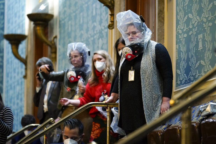 Members of Congress don gas masks while evacuating the House gallery.