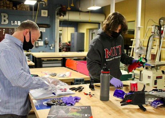 Luka Schulmeyer (right) and Chip Finck (left) build a prosthetic arm during a Robotics Club Meeting