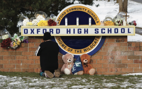 A well-wisher kneels at a memorial created at Oxford High School