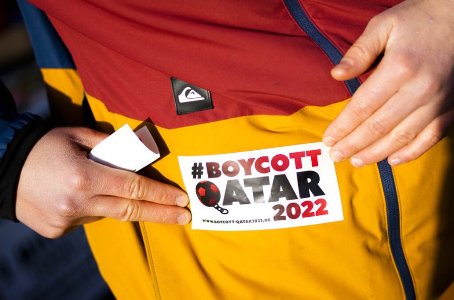 An activist from Extinction Rebellion fixes a sticker on her anorak during a protest against the soccer World Cup being held in Qatar