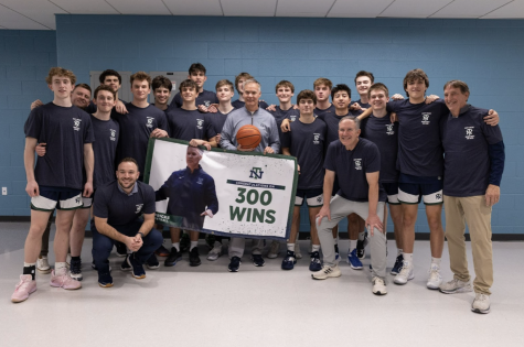 The boys basketball team poses for a picture to celebrate Fricke’s 300th win following victory over  Maine South