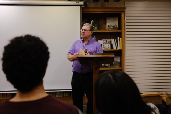 O'Connor stands in the middle of the book stall, the projector behind him