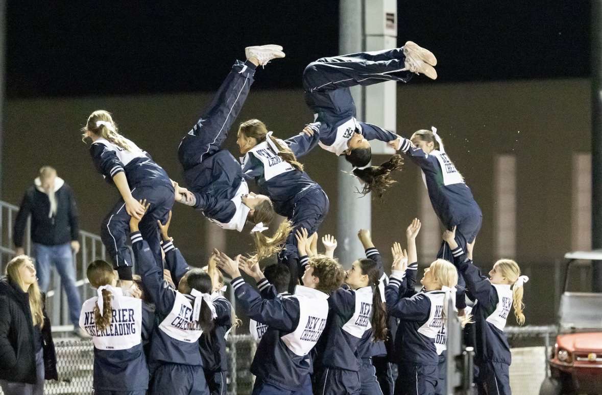 Varsity cheer performs a pyramid and difficult stunts at a varsity football game